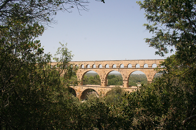 Vue sur le pont du Gard à travers les arbres.
